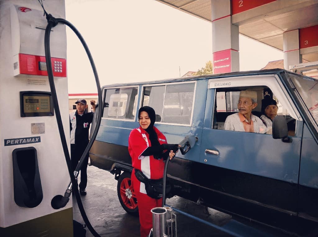 Seorang pengguna mobil sedang mengisi bahan bakar minyak resmi milik pertamina